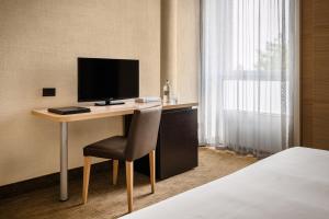 a room with a desk with a television and a chair at Hotel Cora in Carate Brianza