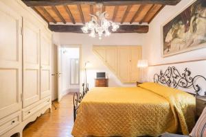 a bedroom with a yellow bed with a chandelier at Vicolo Curtatone 30 in Foiano della Chiana