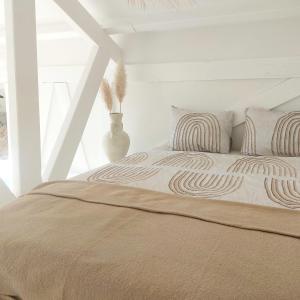 een witte slaapkamer met een bed met 2 kussens bij Casa Pueblo Viejo in Ouddorp