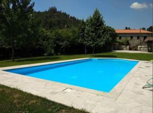 a large blue swimming pool in a yard at Beautiful 2-Bed House - Marco de Canaveses in Marco de Canaveses