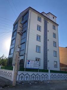 wysoki biały budynek z znakiem przed nim w obiekcie Karakoçan Apart otel w mieście Karakoçan