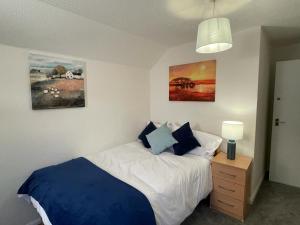 a bedroom with a blue and white bed and a lamp at 3-bedroom home with free parking in Canterbury