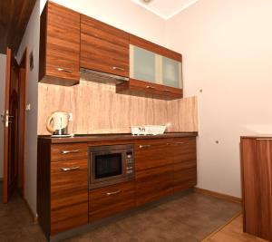 cocina con armarios de madera y microondas en Apartament Mondi Kai II, piękna Willa przy szlaku na Szrenicę, mini SPA, en Szklarska Poręba