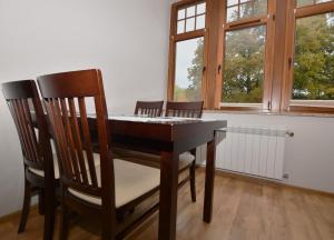 - une table à manger avec 2 chaises et 2 fenêtres dans l'établissement Apartament Mondi Kai II, piękna Willa przy szlaku na Szrenicę, mini SPA, à Szklarska Poręba