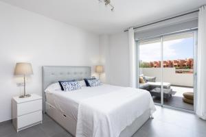 a white bedroom with a bed and a balcony at COSTA MAGALLANES BEACH LA TEJITA in Granadilla de Abona