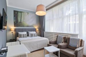 a bedroom with a bed and a couch and a table at Hotel Belle-Vie in Sint-Truiden