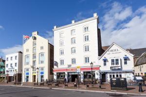 un gran edificio blanco en una calle de la ciudad con bancos en Les Bateaux, en Poole