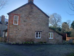 an old brick house with white windows and a fence at Cwmbach Cottage, Hay on Wye in Glasbury