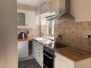 a kitchen with white cabinets and a stove top oven at Cwmbach Cottage nr Hay on Wye in Glasbury