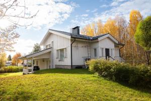 a white house on a grassy yard with trees at Villa Snow White in Rovaniemi