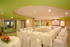 una gran sala de banquetes con mesas blancas y sillas blancas. en Halcyon Hotel Residences Koramangala - Bangalore, en Bangalore