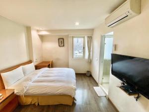 a bedroom with a bed and a flat screen tv at Royal Business Hotel in Hsinchu City