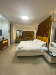 a bedroom with a large white bed and a television at Timeless Apartment and Bar in Lagos