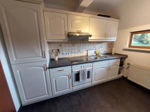 a kitchen with white cabinets and a sink and a stove at Gemütliche Ferienwohnung im Harz in Bad Grund
