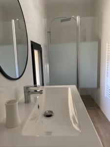 La salle de bains blanche est pourvue d'un lavabo et d'un miroir. dans l'établissement Location de gîte - Mas catalan (66), à Camélas