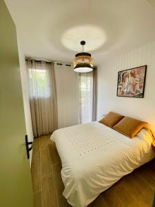 ein Schlafzimmer mit einem großen weißen Bett und einem Kronleuchter in der Unterkunft Petit cocon à Sanary-sur-Mer in Sanary-sur-Mer