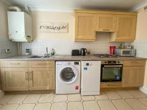 a kitchen with a washing machine and a washer at The Copperfield - Modern 4 Bed house with parking in Canterbury