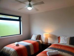 a bedroom with two beds and a ceiling fan at Tranquility in Lakes Entrance
