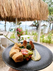 a plate of food with a sandwich on a table at 7SEAS Cottages in Gili Islands