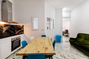 un soggiorno con tavolo in legno e sedie blu di Apartamento en planta baja en badalona, barcelona a Badalona