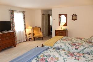 una camera con letto, TV e sedia di Alton Bay Beach House a Alton Bay