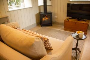 a living room with a couch and a fireplace at The Potting Shed, 5* Luxury escape Cirencester in Cirencester