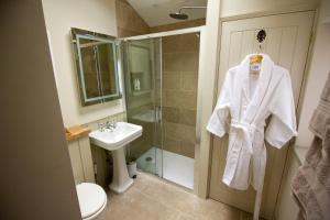 a bathroom with a white robe hanging on a door at The Potting Shed, 5* Luxury escape Cirencester in Cirencester