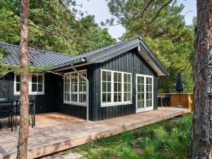 une petite maison noire avec une terrasse dans l'établissement Holiday home Nexø XLI, à Neksø