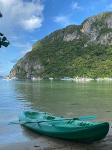 a green kayak sitting on the beach next to a mountain at Sophias Beach Guest House in El Nido +68 photos