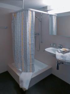 a bathroom with a shower curtain and a sink at Hotel-Restaurant Rosenburg in Wolfhausen