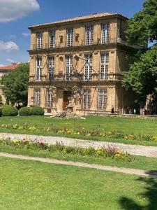 - un grand bâtiment en pierre avec un jardin en face dans l'établissement BLUE FOUNTAIN Luxueux Studio Aix Centre Historique -WIFI-SMART TV-, à Aix-en-Provence