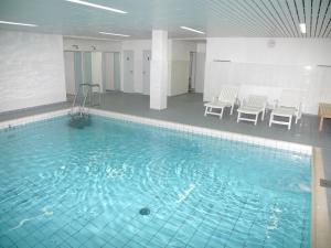 een groot zwembad met blauw water in een gebouw bij Haus Norderhoog Wohnung 47 in Westerland