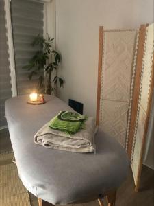 Una cama con una vela y toallas. en Au Petit C'Alain en Toulouse