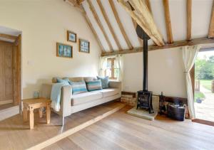 a living room with a couch and a wood stove at Bluebell Byre in Rolvenden