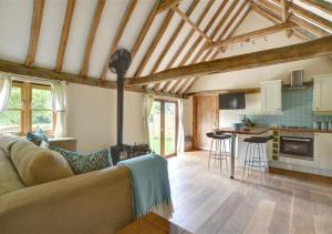 a living room with a couch and a kitchen at Bluebell Byre in Rolvenden