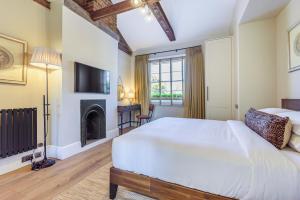 1 dormitorio con 1 cama blanca grande y chimenea en Oak & Poppy, en Londres