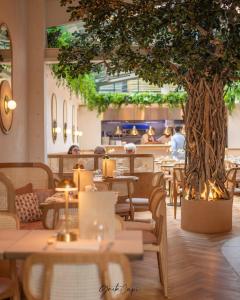 restauracja ze stołami i drzewem w środku w obiekcie Oak & Poppy w Londynie