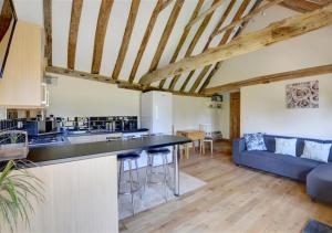 an open kitchen and living room with a blue couch at Barley Byre in Rolvenden