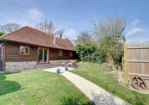 a wooden house with a fence and a yard at Barley Byre in Rolvenden