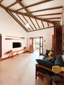 a living room with a couch and a tv at Bangalô de Charme na Praia do Patacho - Rota Ecológica dos Milagres in Pôrto de Pedras +23 photos