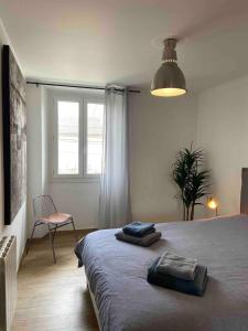 a bedroom with a bed and a chair and a window at Appartement avec climatisation proche du centre in Morières-lès-Avignon