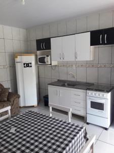 a kitchen with a stove and a white refrigerator at Apartamentos C. Santos in Penha