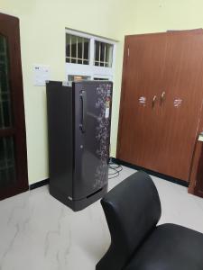 a black refrigerator in a room with a chair at Sri Sai Farm House in Puducherry