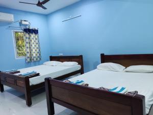 two beds in a room with blue walls at Sri Sai Farm House in Puducherry
