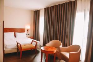 a hotel room with a bed and a chair and a table at Hotel dei Cavalieri Caserta - La Reggia in Caserta