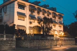 ein großes weißes Gebäude mit einem Baum davor in der Unterkunft Eveline Portosole Hotel in Sanremo