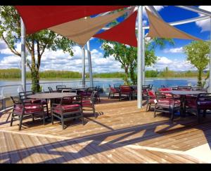 une terrasse avec des tables et des chaises offrant une vue sur l'eau dans l'établissement Bungalow 2/4 personnes dans résidence Hôtelière, à Meyzieu