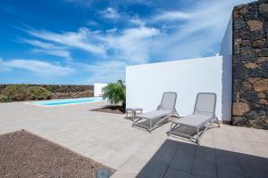 two chairs sitting on a patio next to a pool at North Shore Villas, Villa MAKAI, Heated & Shared Pool in Lajares