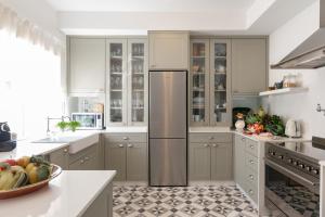 uma cozinha com armários brancos e um frigorífico de aço inoxidável em Casa da Avó Bia em Estremoz