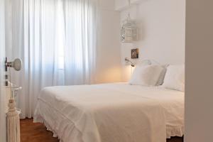 a white bedroom with a white bed and a window at Casa da Avó Bia in Estremoz